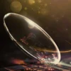 Glowing premium optical lens with warm golden halo light and reflective surface.